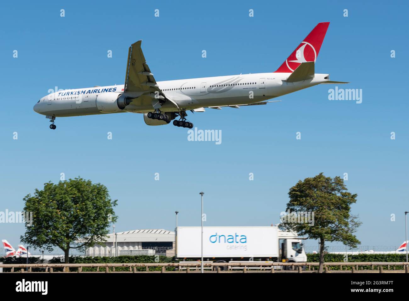 Turkish Airlines Boeing 777 airliner jet plane TC-LJH  on finals to land at London Heathrow Airport, UK, over A30 road and catering business lorry Stock Photo