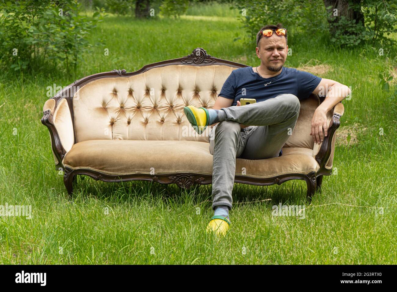 Mid aged man relaxes sitting at comfortable home sofa in garden outdoors. High quality photo Stock Photo