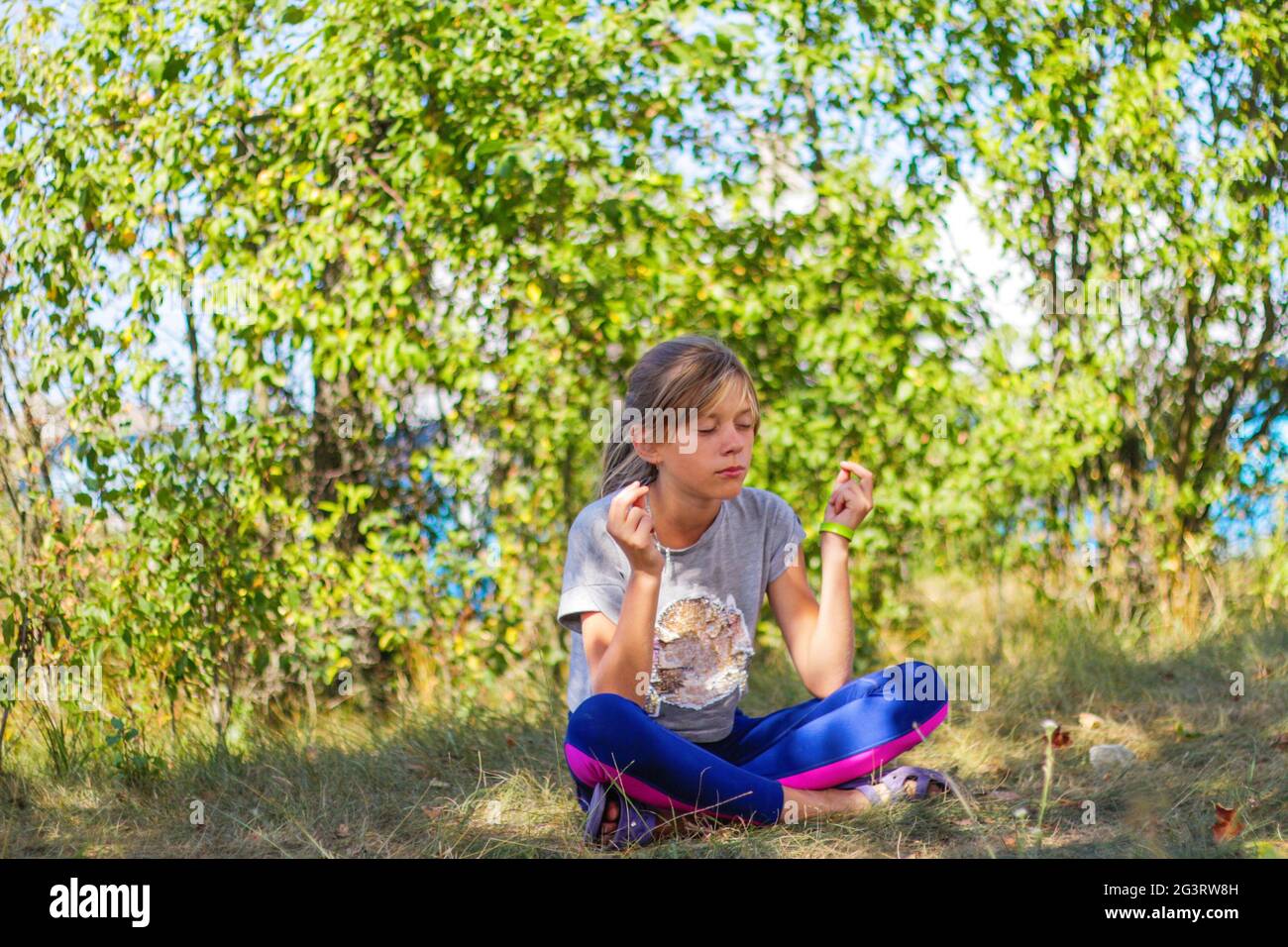Defocus caucasian preteen girl practicing yoga in park, forest, outdoor, outside. Meditation and concentration. Wellness healthy lifestyle. Yoga girl. Stock Photo