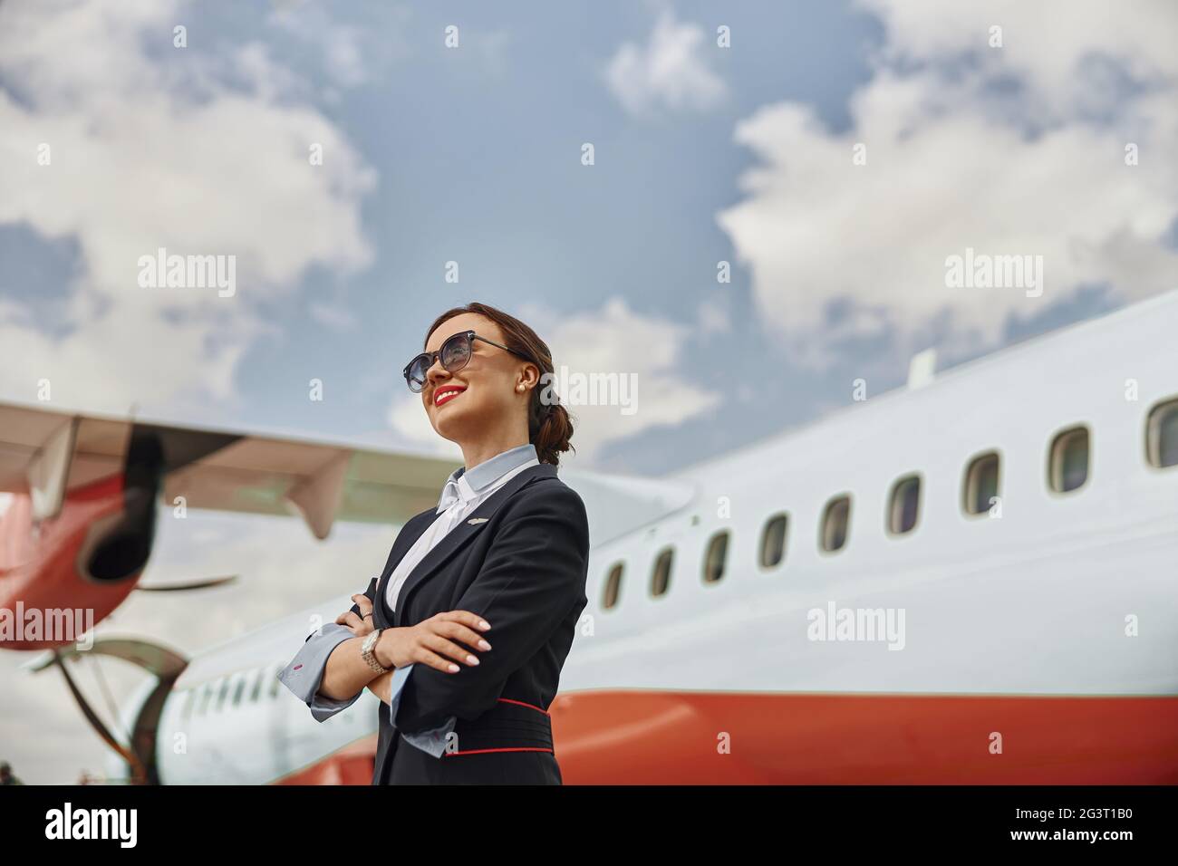 Smiling stewardess on runway near airplane jet Stock Photo