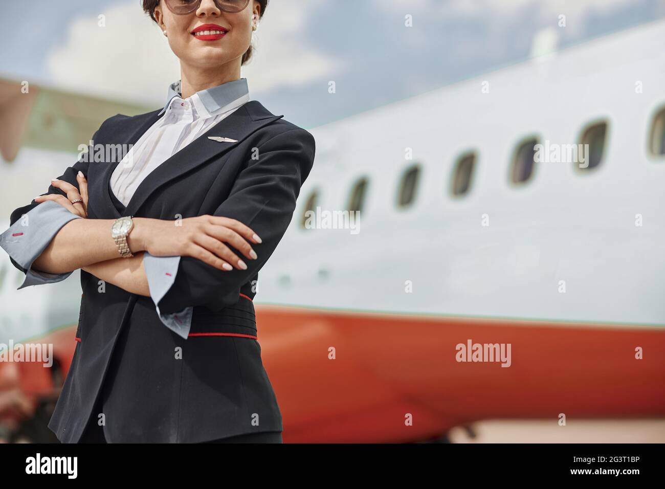 Smiling stewardess on runway near airplane jet Stock Photo