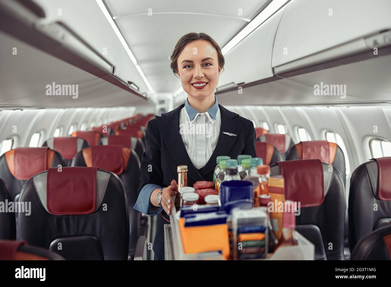 Stewardess carrying food trolley in airplane cabin Stock Photo Alamy