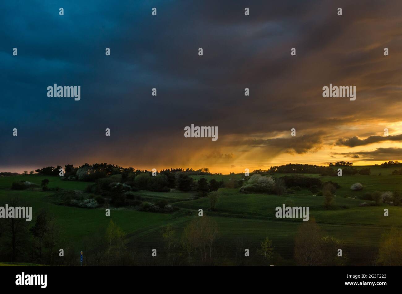 Dramatic cloudy sky at sunset over hilly grass covered landscape in Eifel, Germany Stock Photo
