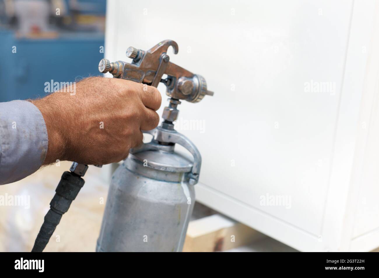 Painting of a metal product. Close up of a painter's hand with a