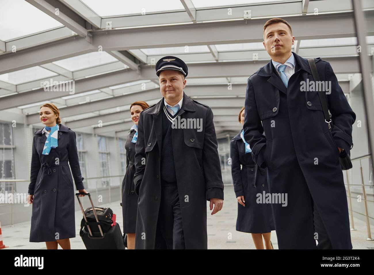 Plane team with baggage near entrance of airport Stock Photo