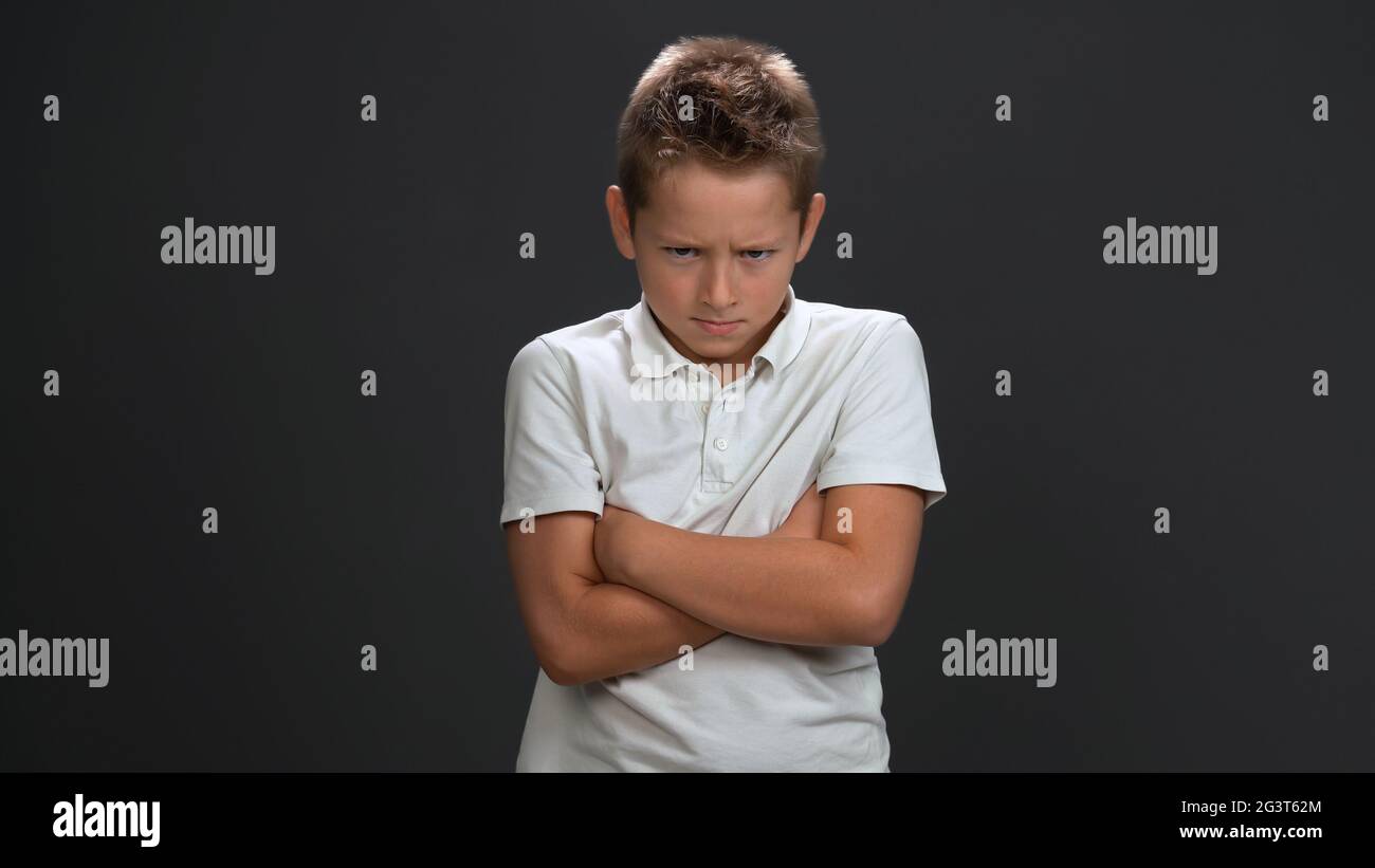 Angry schoolboy crossed hand frowning face. Isolated on gray background. Copy space Stock Photo