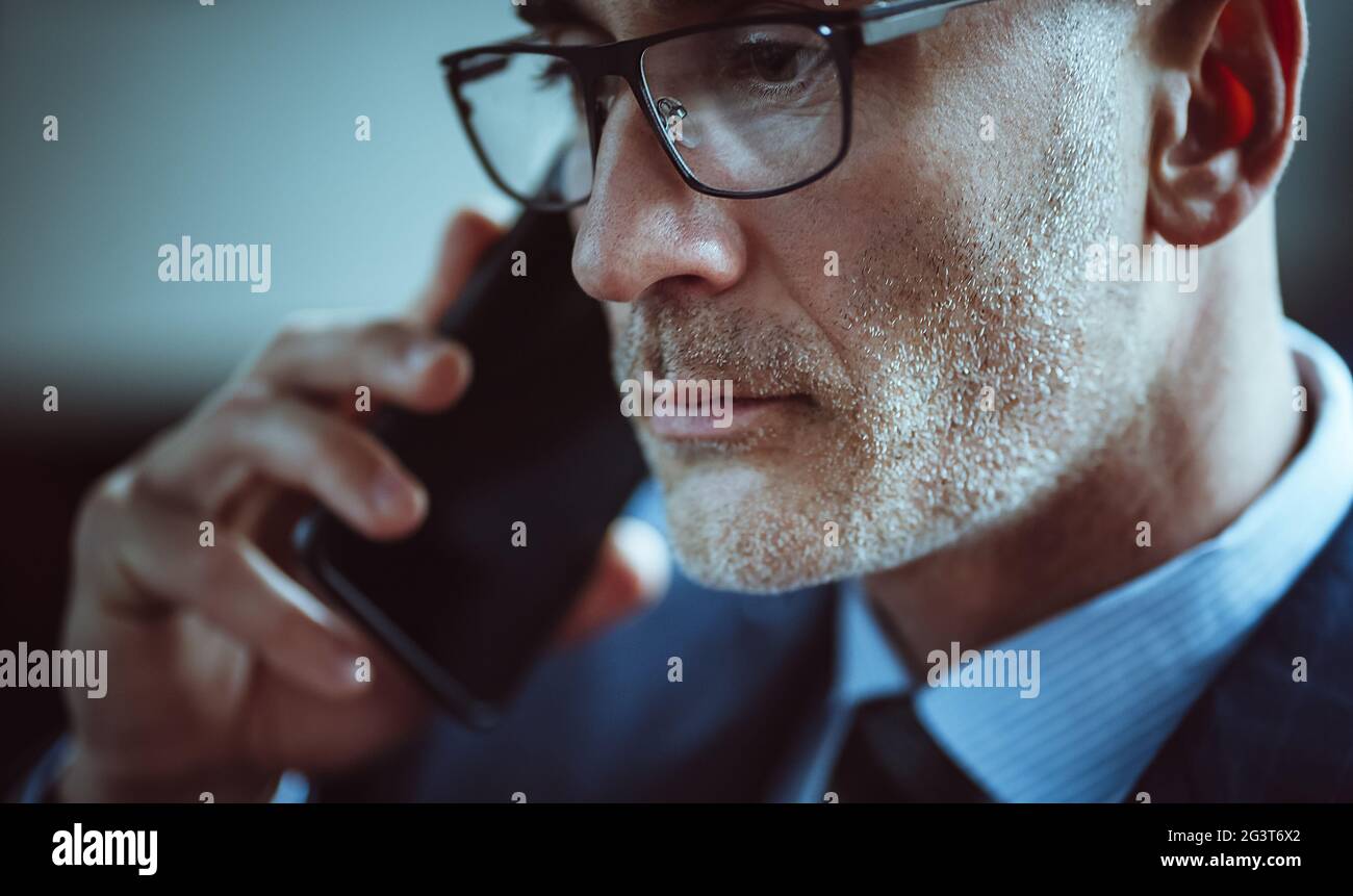 Handsome businessman talks on mobile phone. Close up portrait of Caucasian man with gray stubble answering the call. Business co Stock Photo