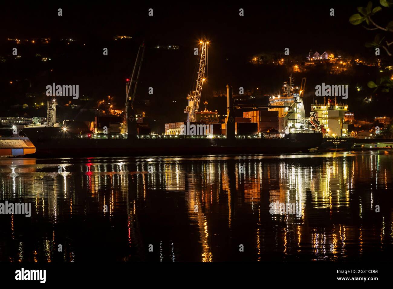 Container cargo vessels being offloaded at night time Stock Photo