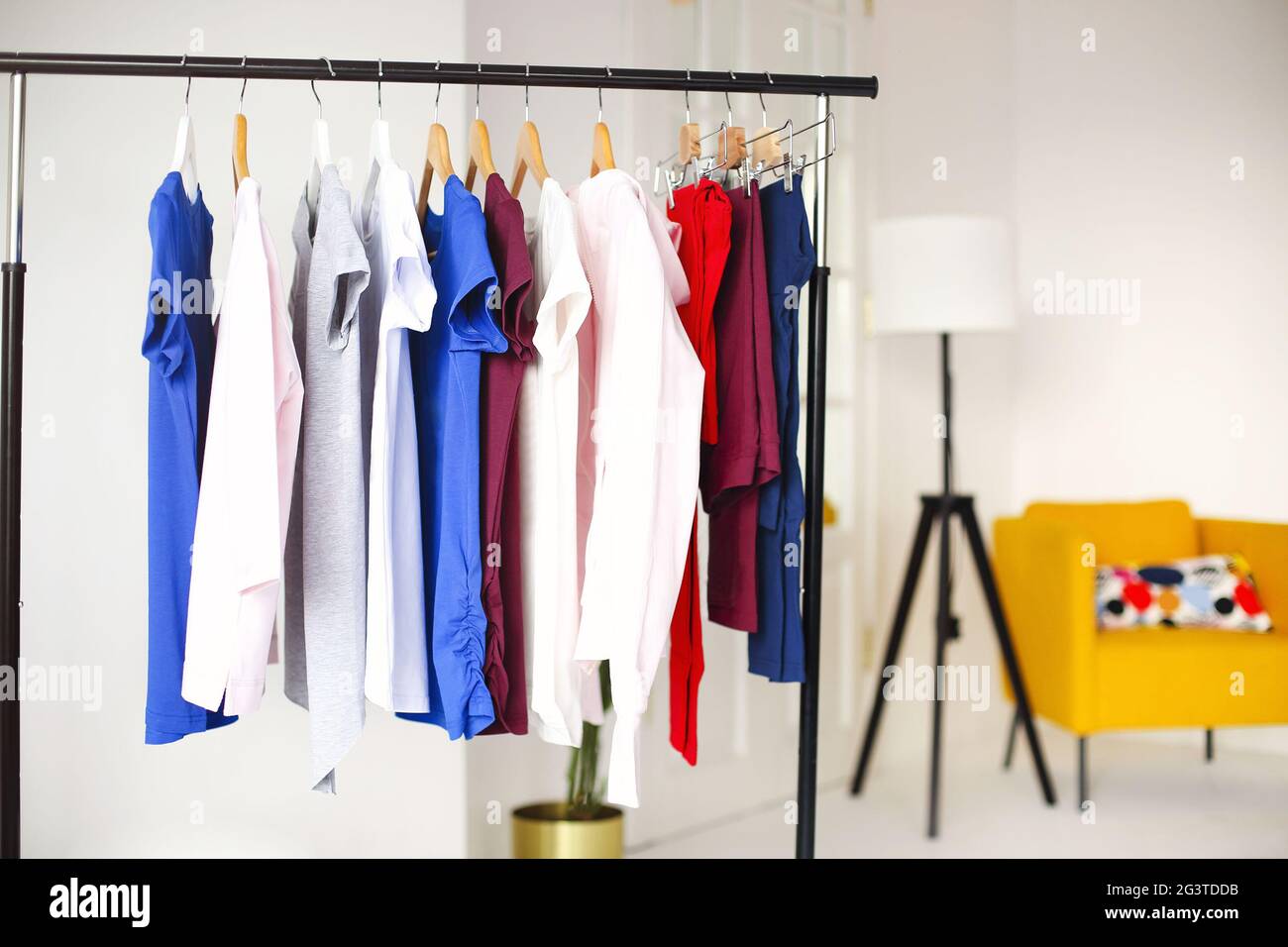 Colorful clothes hanging on rack in room Stock Photo Alamy