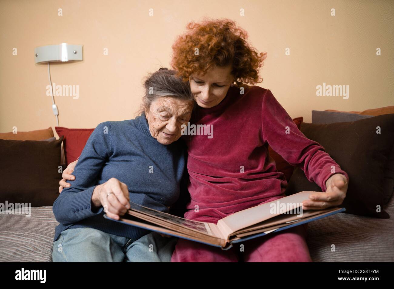 Senior woman and her adult daughter looking at photo album together on ...