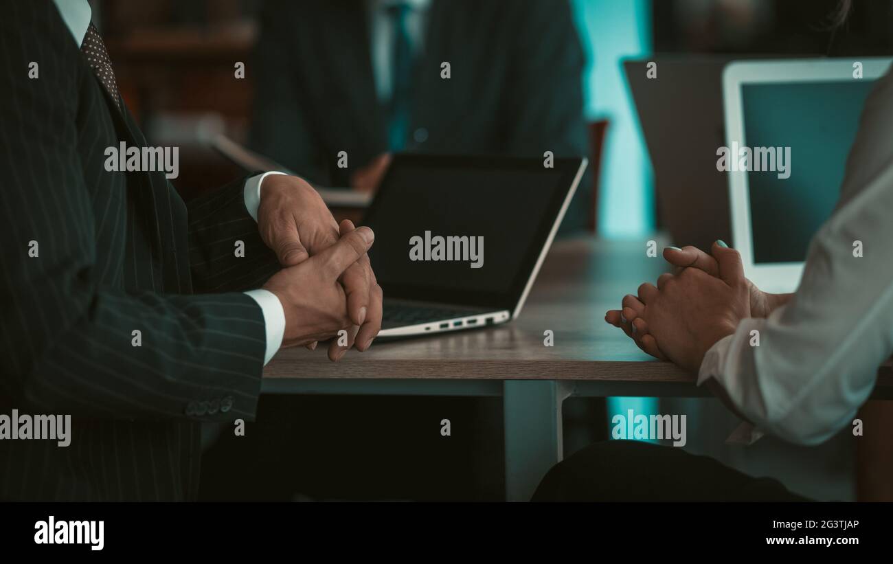 Two adult business people having a conversation sitting at the table with laptop computers in an office at desk, working in the Stock Photo