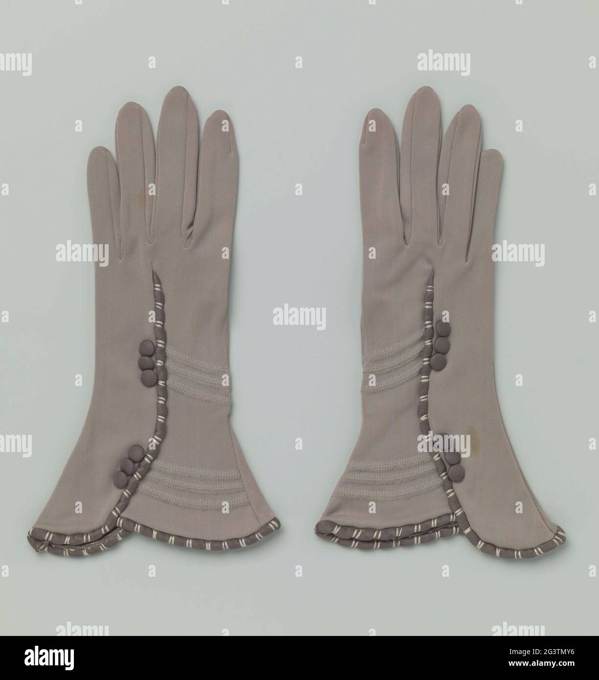 https://c8.alamy.com/comp/2G3TMY6/pair-of-gloves-with-cut-on-cuffs-right-gloves-of-mouse-gray-nylon-realed-impeller-shaped-caps-on-the-basis-of-a-semicircular-flared-natment-in-which-a-padded-band-rouleaux-anthracite-colored-nylon-is-attached-this-band-with-white-loops-divides-into-small-compartments-continues-along-the-edge-of-the-hood-on-the-hand-and-at-the-wrist-there-are-three-anthracite-nylon-buttons-on-one-side-next-to-the-band-and-three-filled-stitched-tires-on-the-other-side-2G3TMY6.jpg