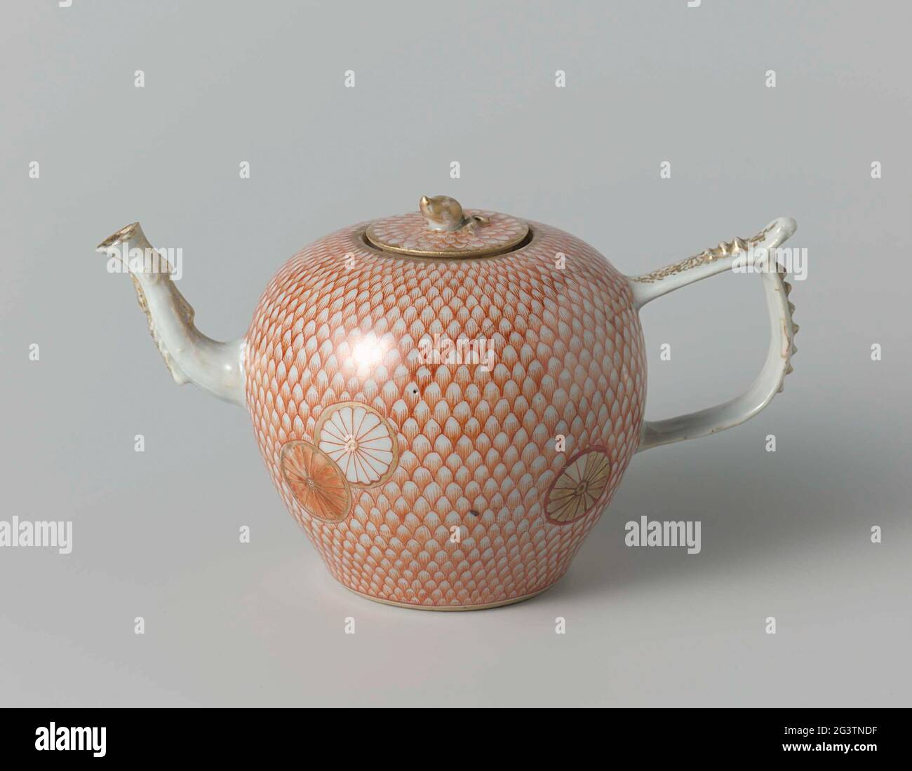 Ovoid Teapot With Stylized Flowers on a Feather or Scale Ground and Scrolls. Egg-shaped teapot of porcelain with curved spout and j-shaped ear, painted on the glaze in red and gold. On the abdomen six stylized flowers against a background of a spring or schub motif; Ranked on the ear and the spout. Lid with the same decoration. Part of a tea service. European forms with email colors. Stock Photo