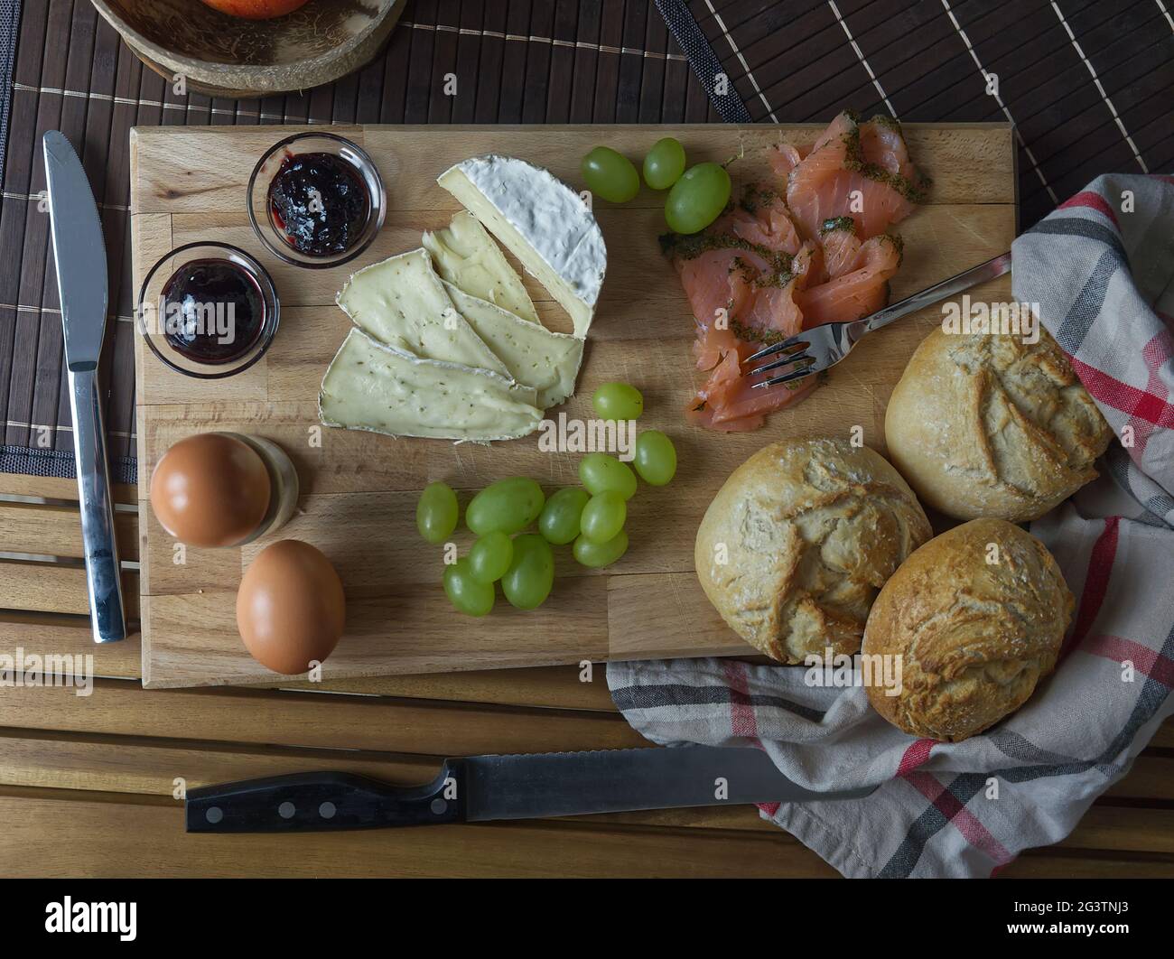 A tasty european breakfast with eggs, salmon, grapes, cheese and rolls topview Stock Photo