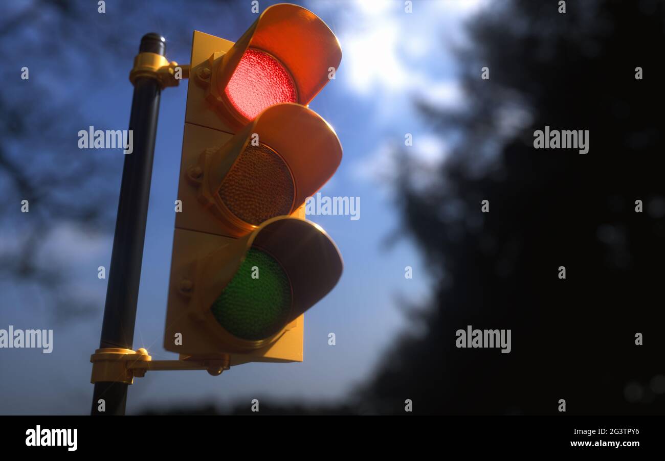Outdoor vertical traffic light with blue sky and trees around. Traffic control concept image with shallow depth of field. Stock Photo
