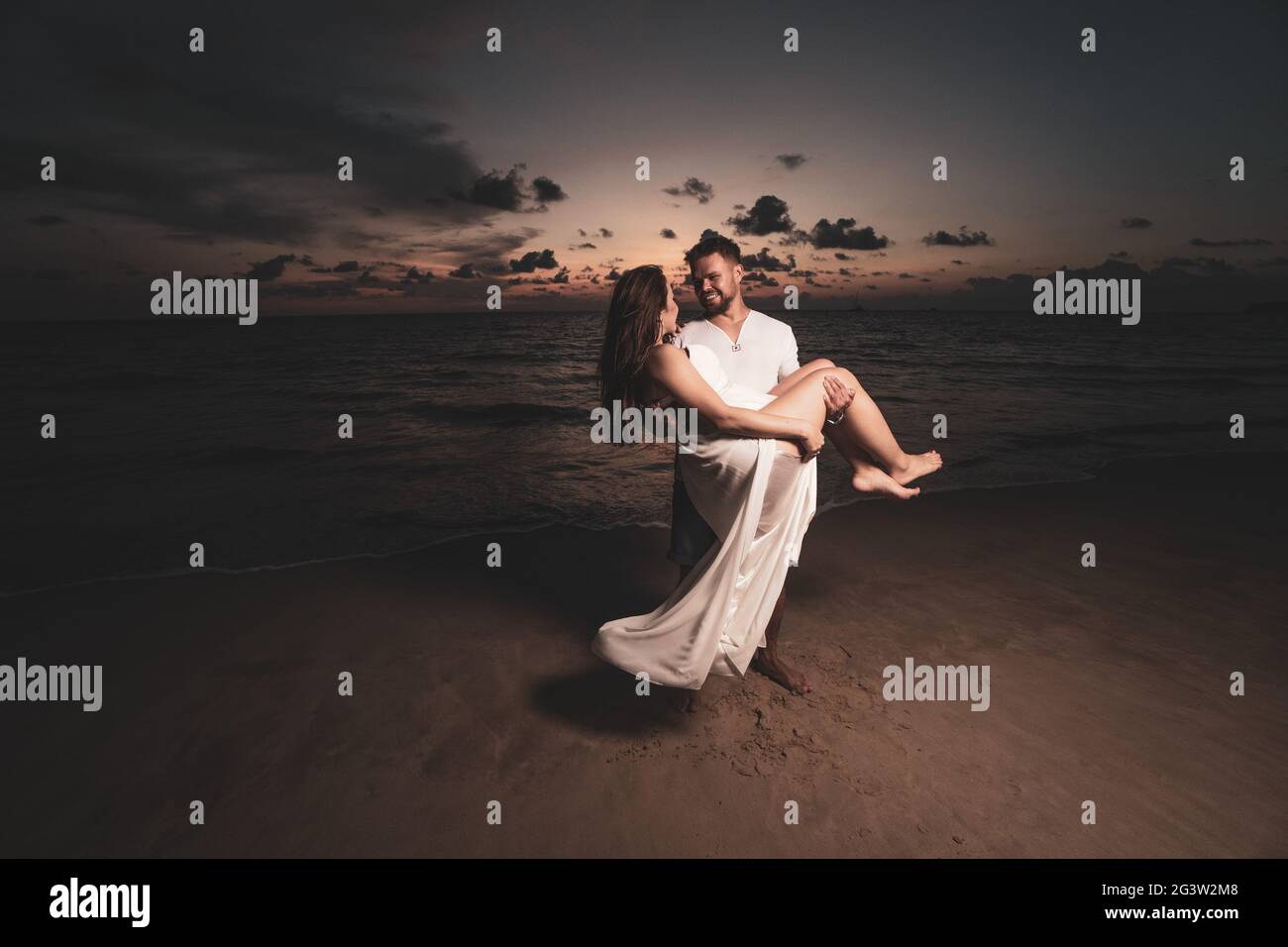 Romantic couple on th beach during sunset Stock Photo - Alamy