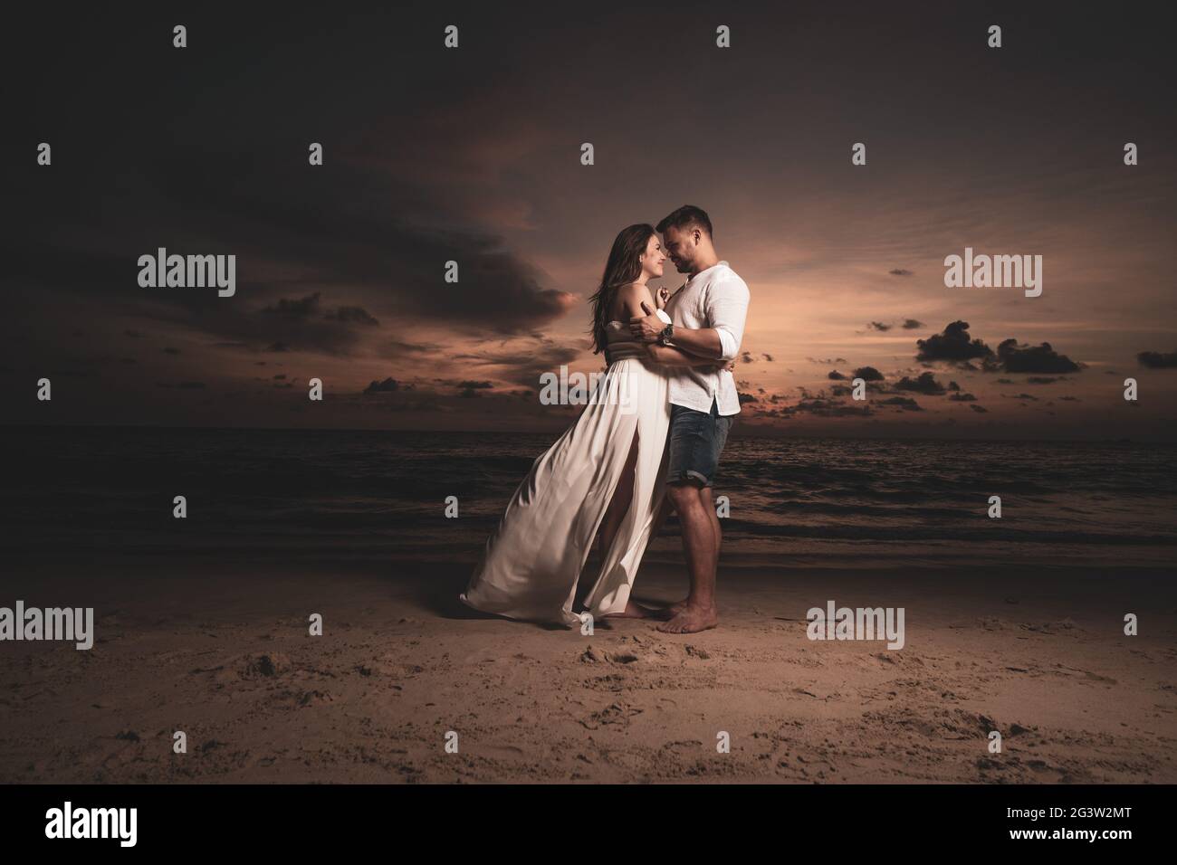 Romantic couple on th beach during sunset Stock Photo - Alamy