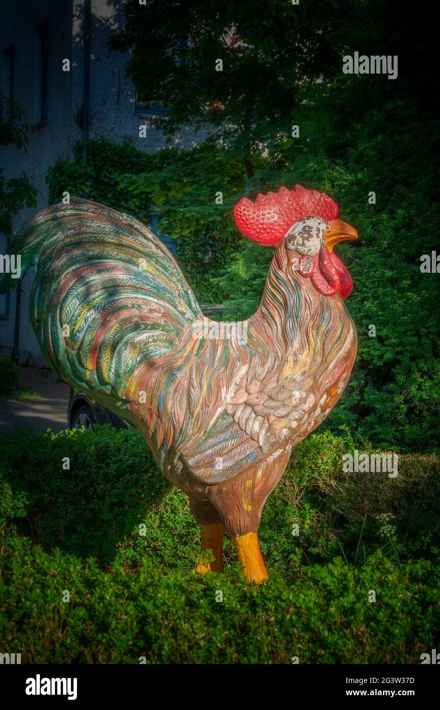 BUNDE, GERMANY. JUNE 12, 2021. Beautiful view of small german town. Small statue of cock on the yard. Stock Photo
