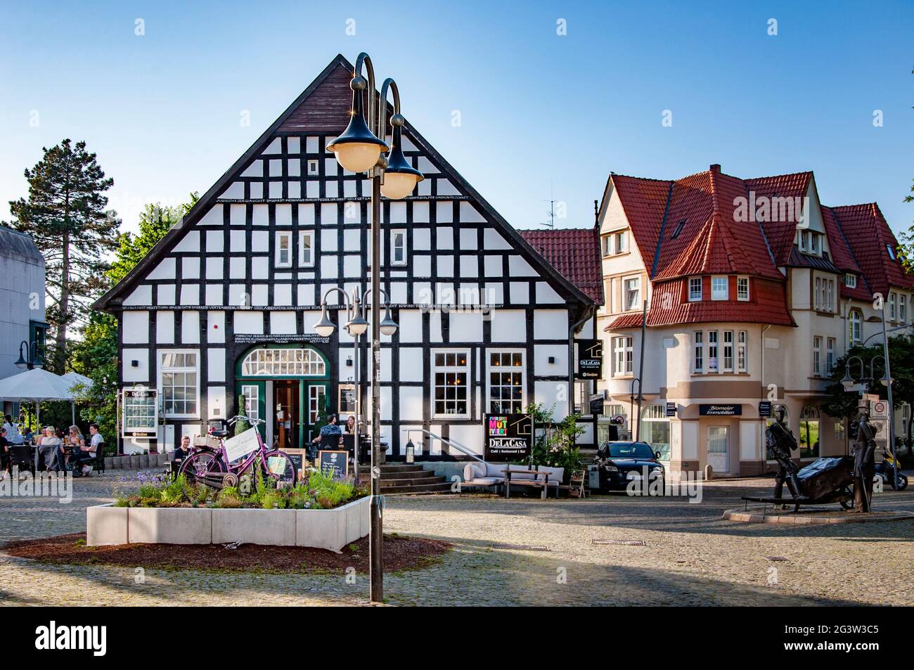 BUNDE, GERMANY. JUNE 12, 2021. DeLaCasa restaurant on the square, pink bicycle before the entrance with advertizing of apiary Land Frauen. Beautiful v Stock Photo