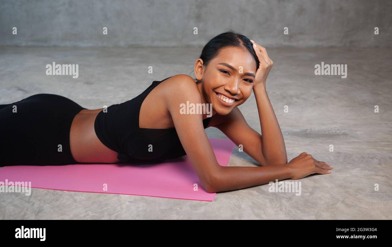 Happy healthy smiling woman posing relaxing on the pink yoga mat at the ...