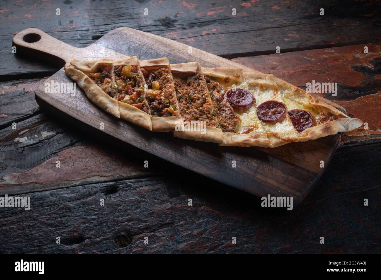 Turkish pide with sausage, beef and vegetables on rustic wooden table Stock Photo