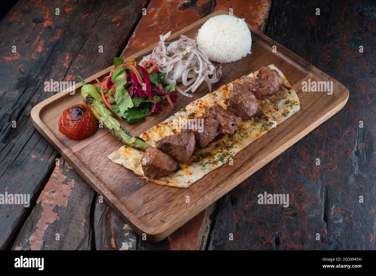 Turkish lamb sis kebab with rice and vegetables on rustic wooden table Stock Photo