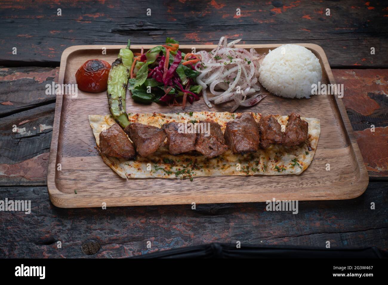 Turkish lamb sis kebab with rice and vegetables on rustic wooden table Stock Photo