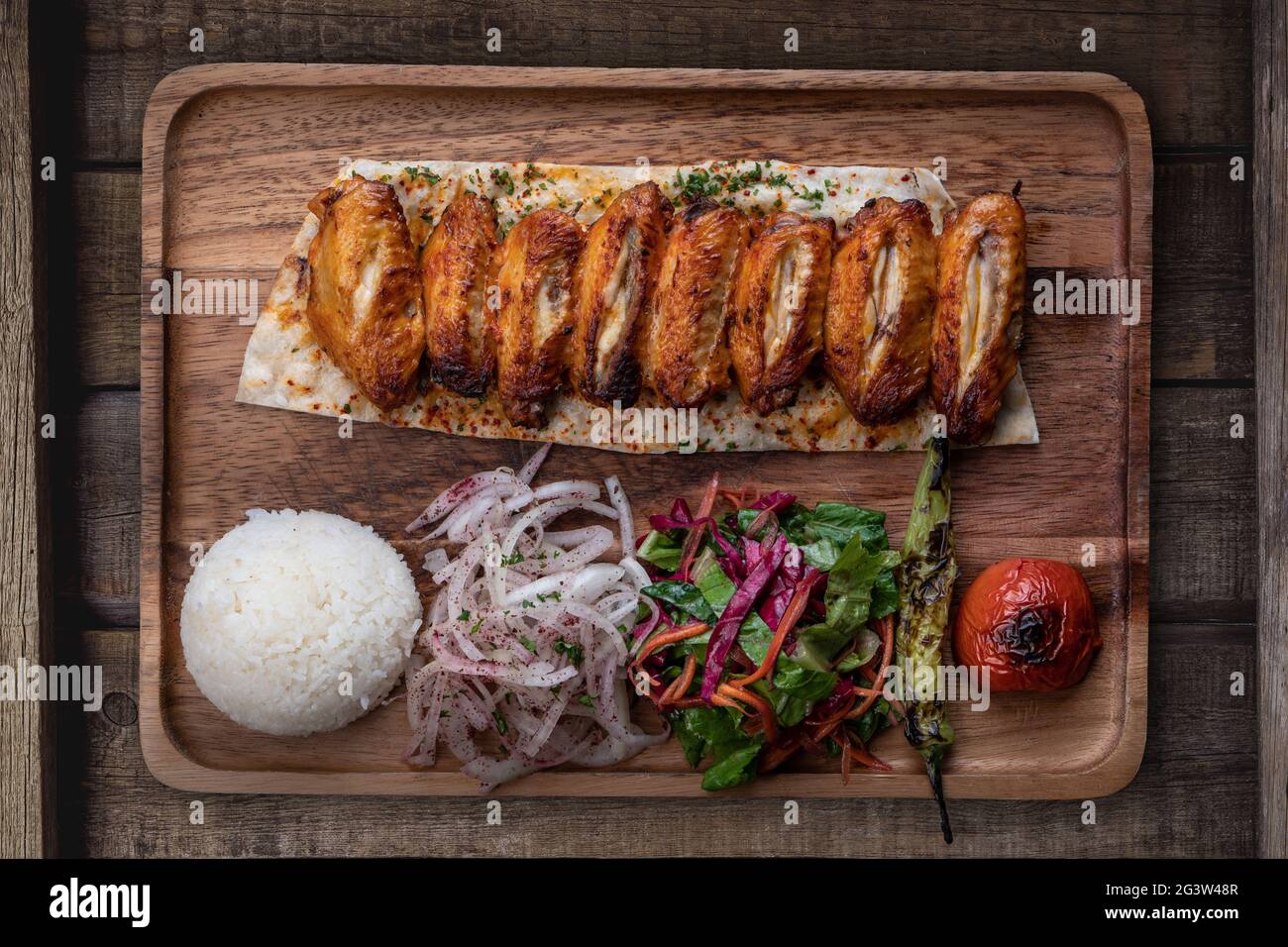 Turkish chicken wings kebab with rice and vegetables on rustic wooden