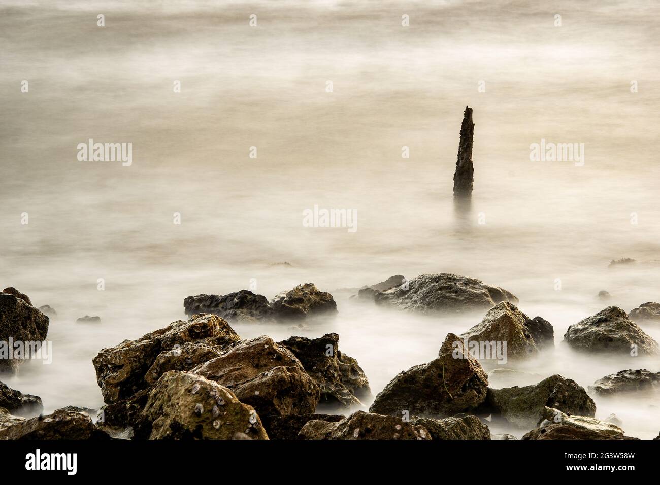 Scenic misty sea with a tall sea stack in the distance Stock Photo - Alamy