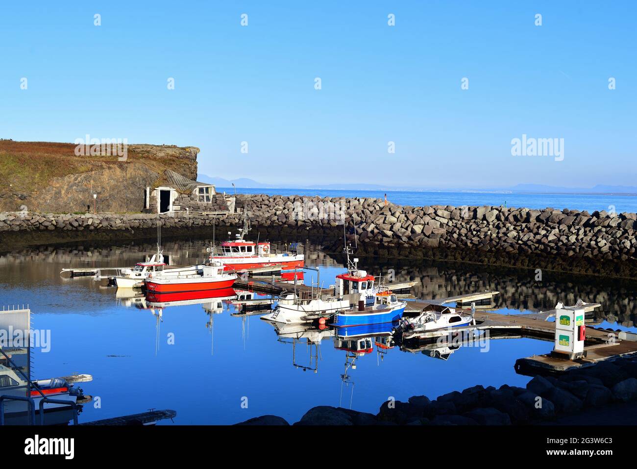 Reykjanesbaer, Iceland. A high, rocky breakwater provides a safe haven from North Atlantic Ocean waters for some fishing boats and small craft. Stock Photo