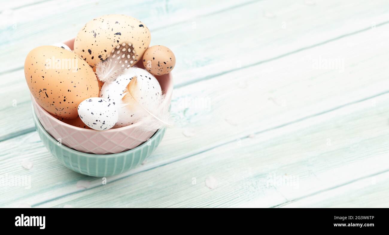 Chicken and quail eggs in bowl on wooden table. Easter eggs. With copy space Stock Photo