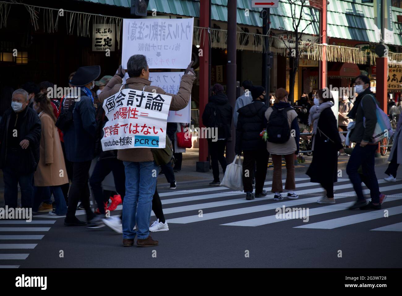 Japanese male holding Covid Conspiracy and anti covid-19 vaccine poster along Kaminarimon-Dori Street during Japan's Oshogatsu, Asakua, Tokyo, Japan Stock Photo