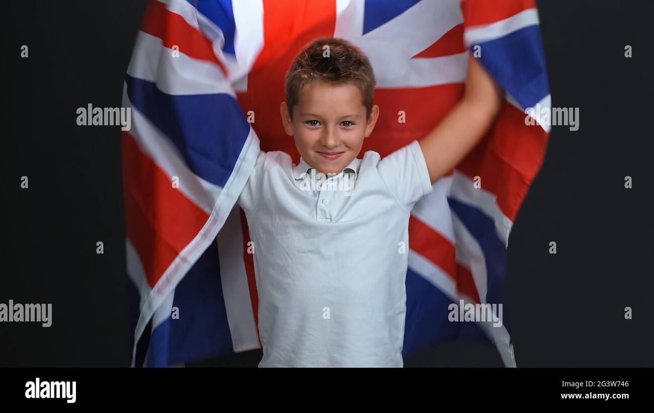 Happy little boy holding the flag of England or Great Britain, celebrating independence day expresses patriotism isolated on bla Stock Photo