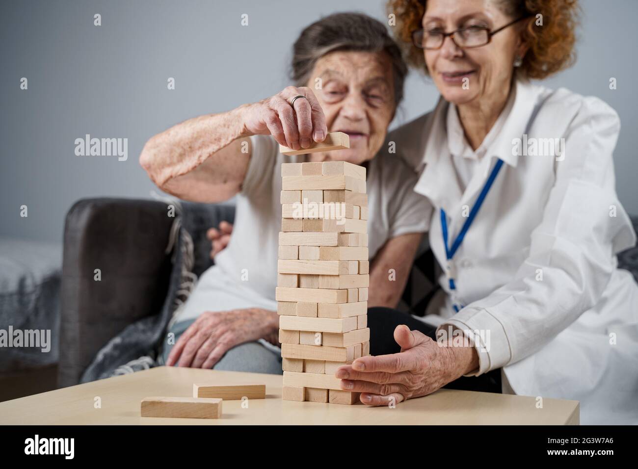 Mature doctor conducting session, therapy for senior patient in nursing home, training fine motor skills for dementia, alzheimer Stock Photo