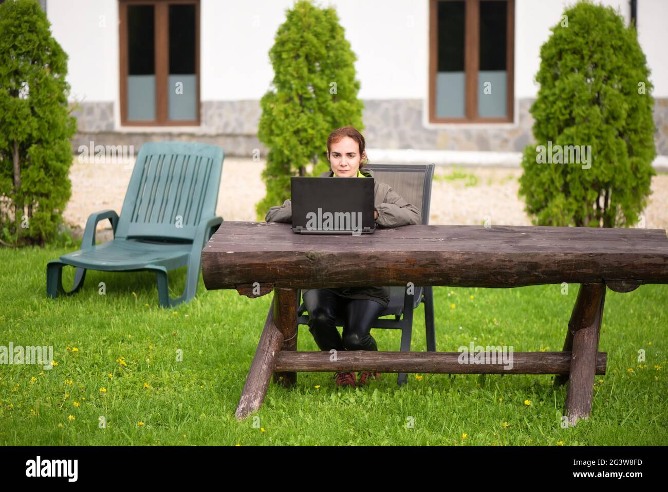 Woman working in nature with laptop on a wooden table Stock Photo