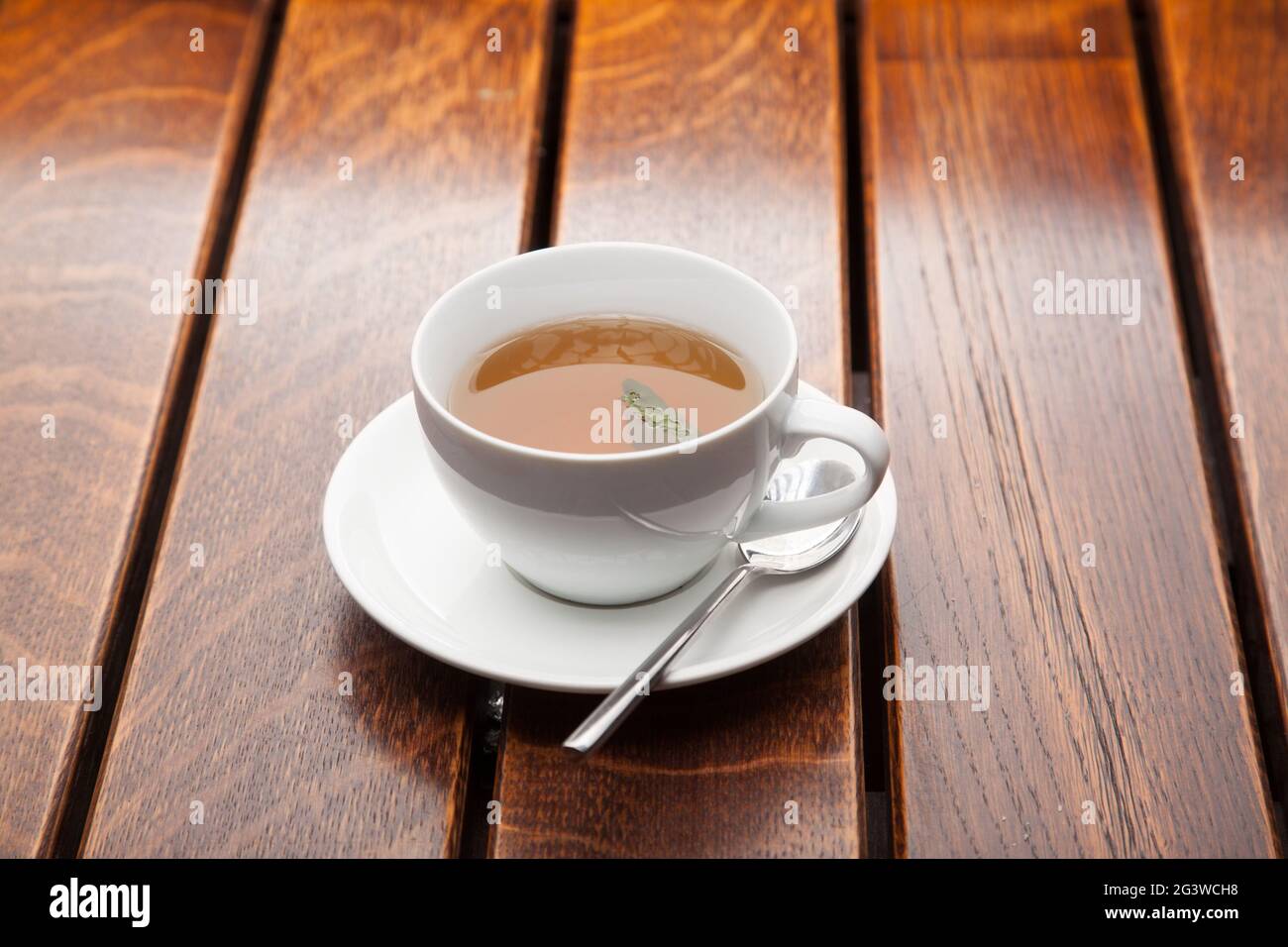 Cup of green tea on wooden table, evening relaxation. Black strong tea in a white mug. Stock Photo