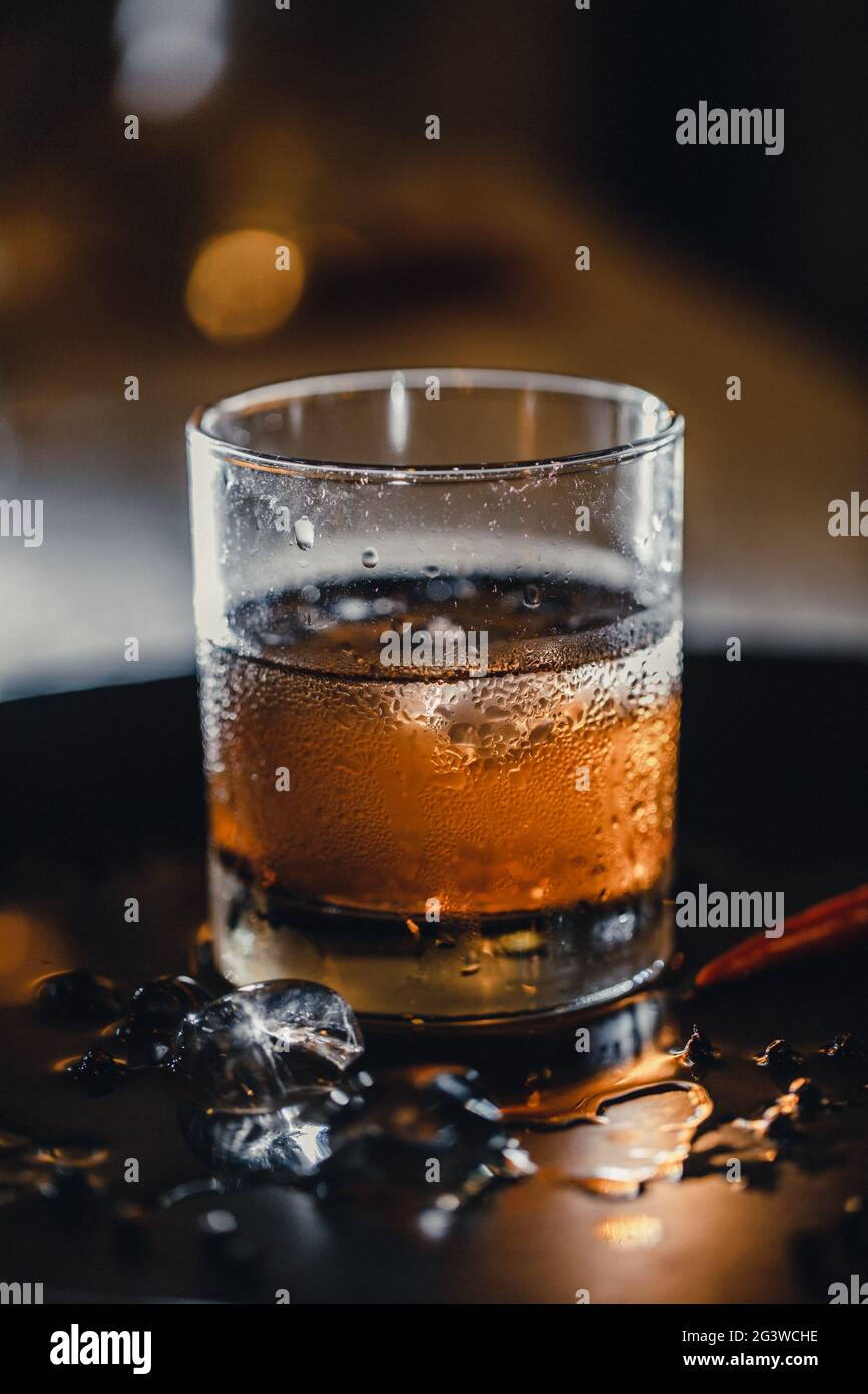 Cocktail - whiskey with ice in a shot. Bar cocktail whiskey and cola. Cold ice in a glass of whiskey. Stock Photo