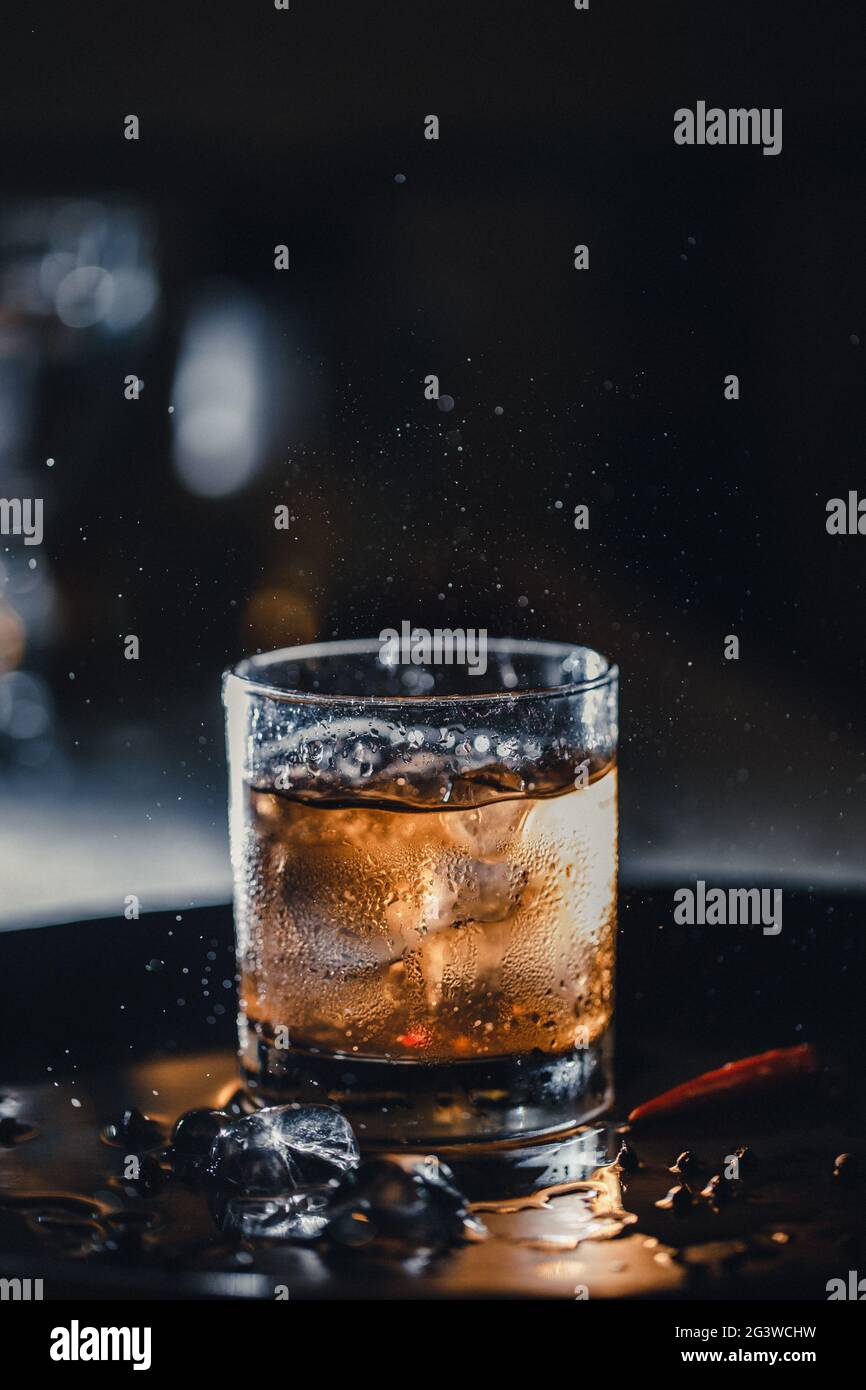 Cocktail - whiskey with ice in a shot. Bar cocktail whiskey and cola. Cold ice in a glass of whiskey. Stock Photo