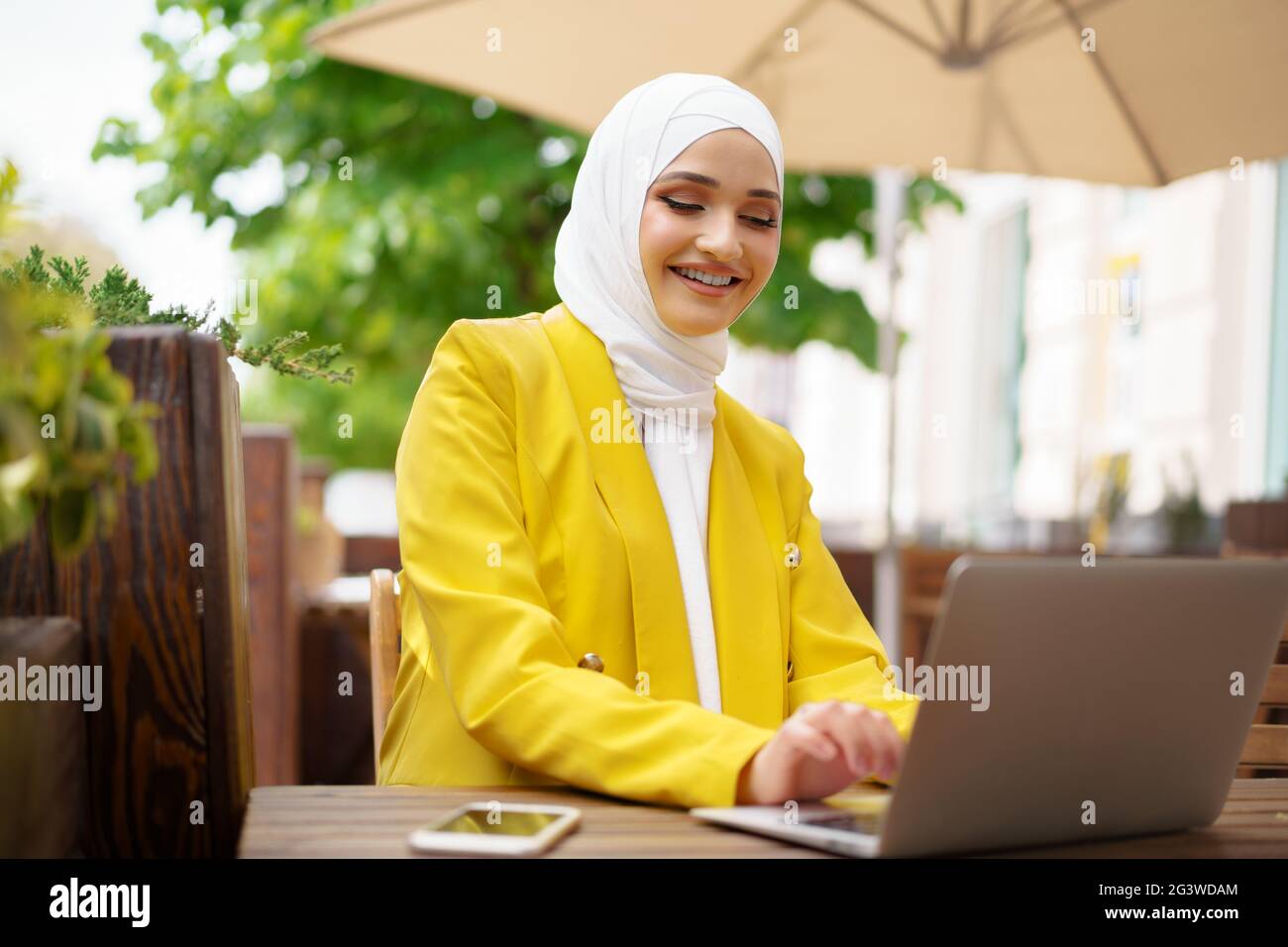 Beautiful smiling muslim woman with laptop at cafe Stock Photo - Alamy
