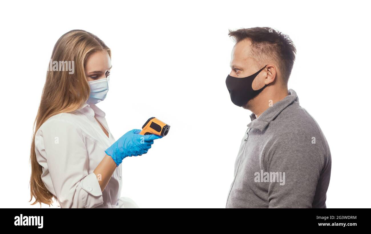 Looking at non-contact thermometer nurse testing employee's or patients body temperature wearing a medical face mask. Sad man we Stock Photo