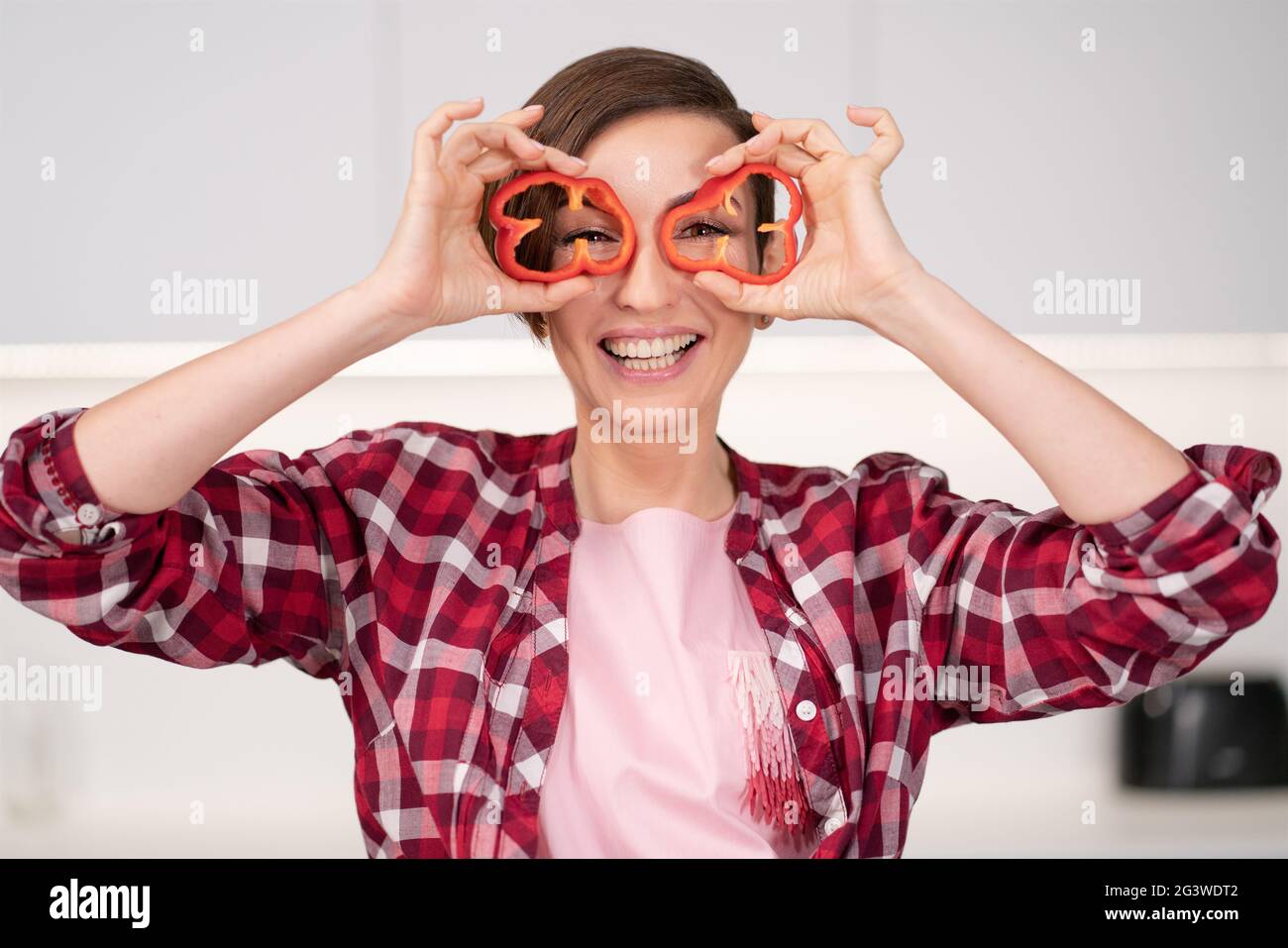 Short hair woman in red shirt playing with food, cut slices of sweet paper while cooking in the white kitchen. Healthy food at h Stock Photo