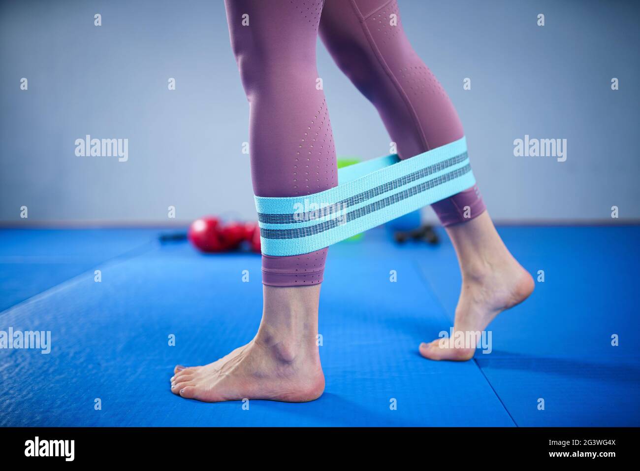 Athletic woman in sportswear barefoot using thick elastic fabric workout bands for stretch fitness booty loops, band for gym, we Stock Photo
