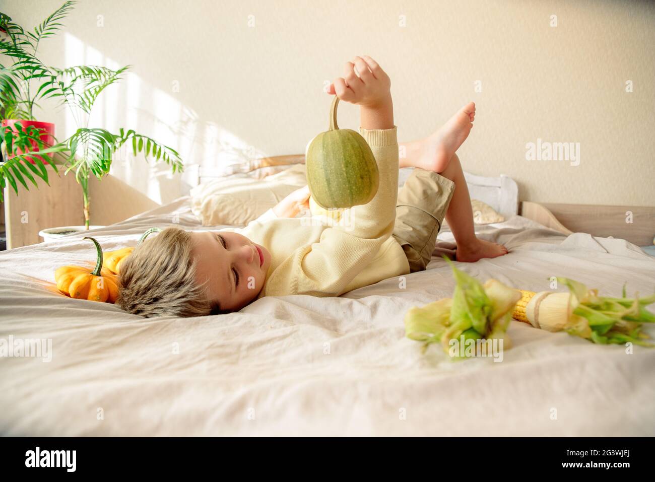 child plays at home on the bed, autumn lifestyle Stock Photo Alamy