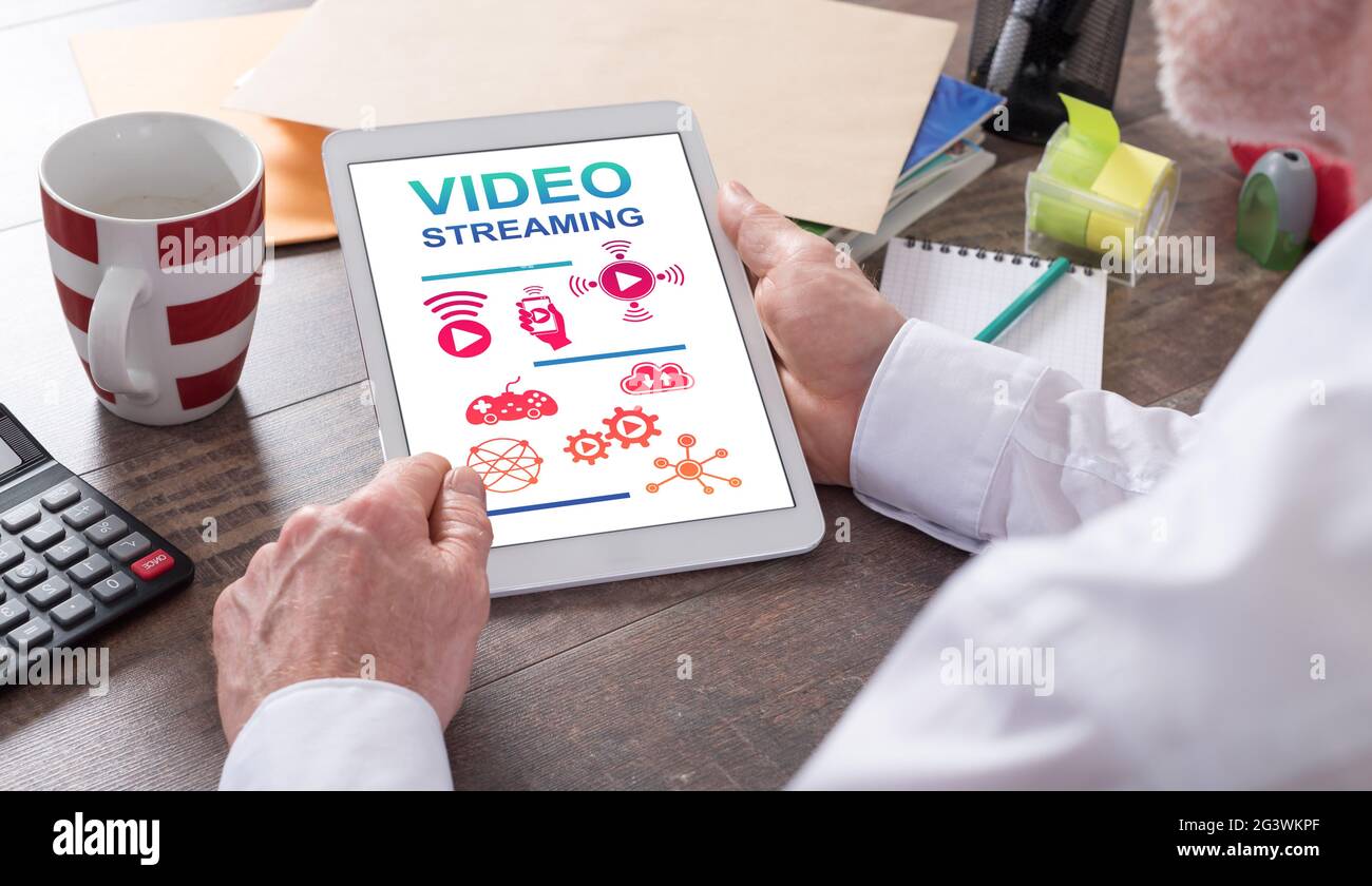 Video streaming concept shown on a tablet held by a man Stock Photo