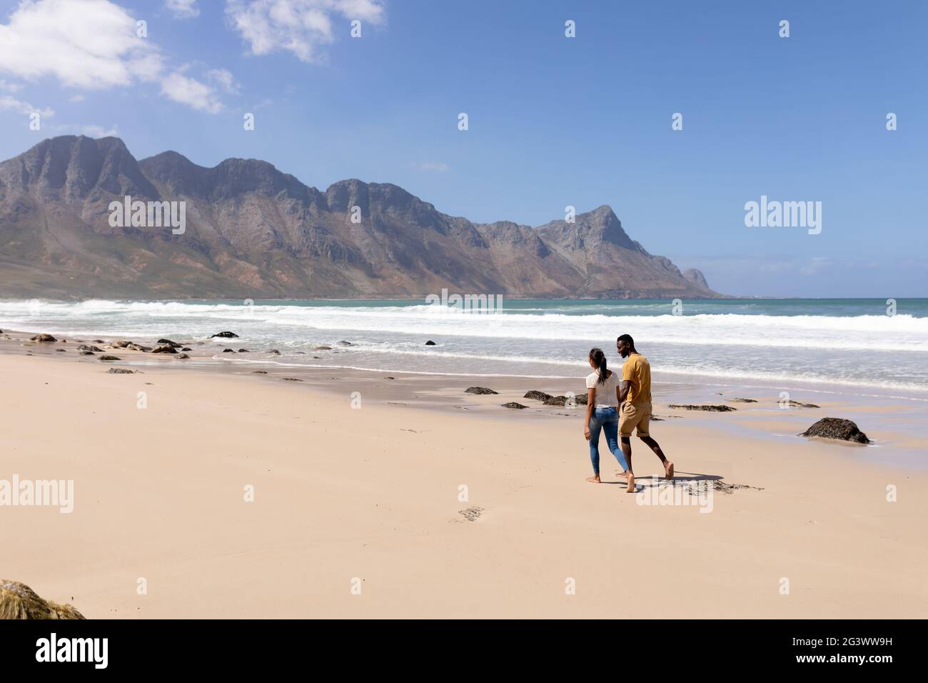 African american couple walking holding hands on a beach by the sea ...