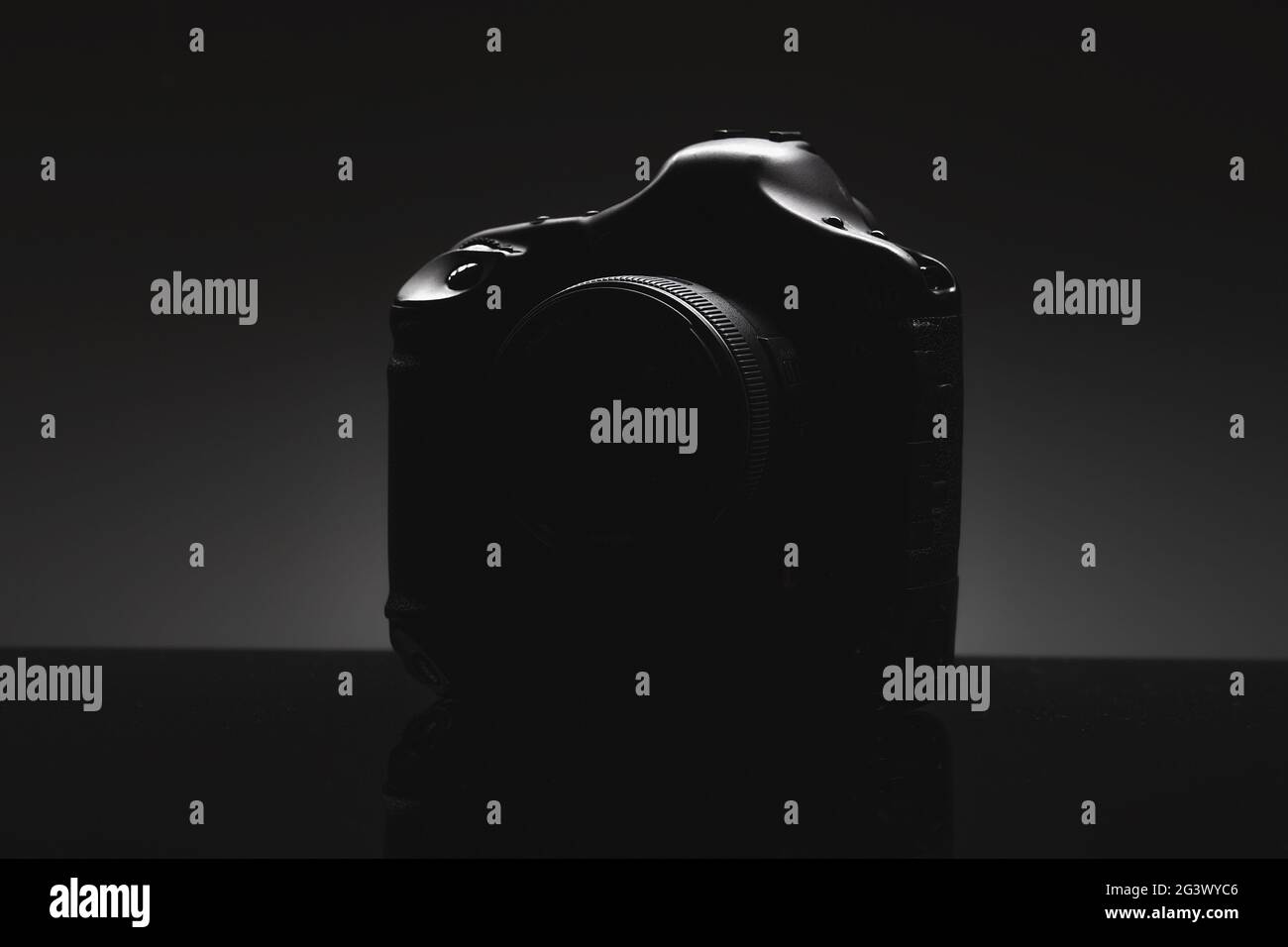 The silhouette of a professional SLR camera on a black background. Presentation of a new product Stock Photo
