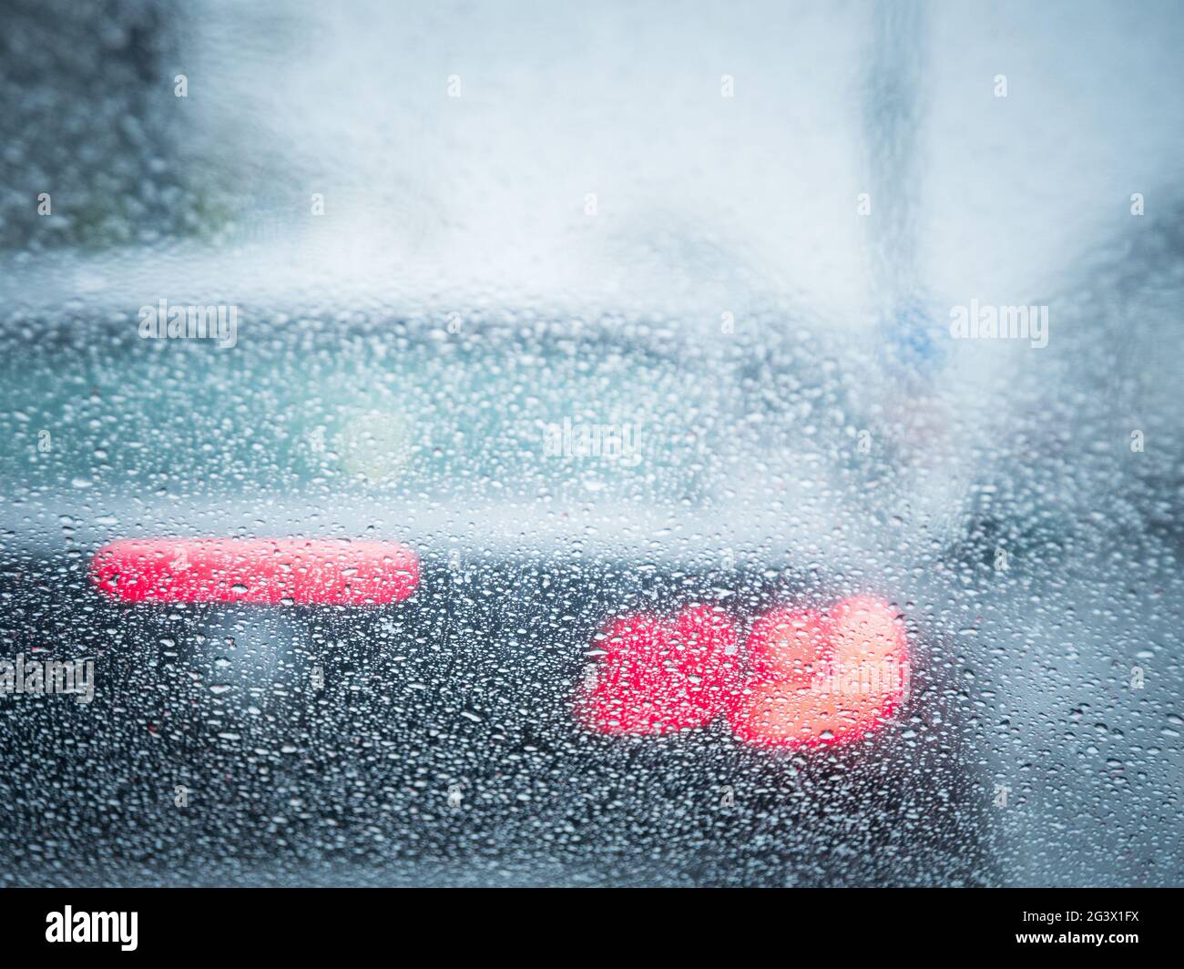 Red backlight of a car in the rain focus on raindrops Stock Photo