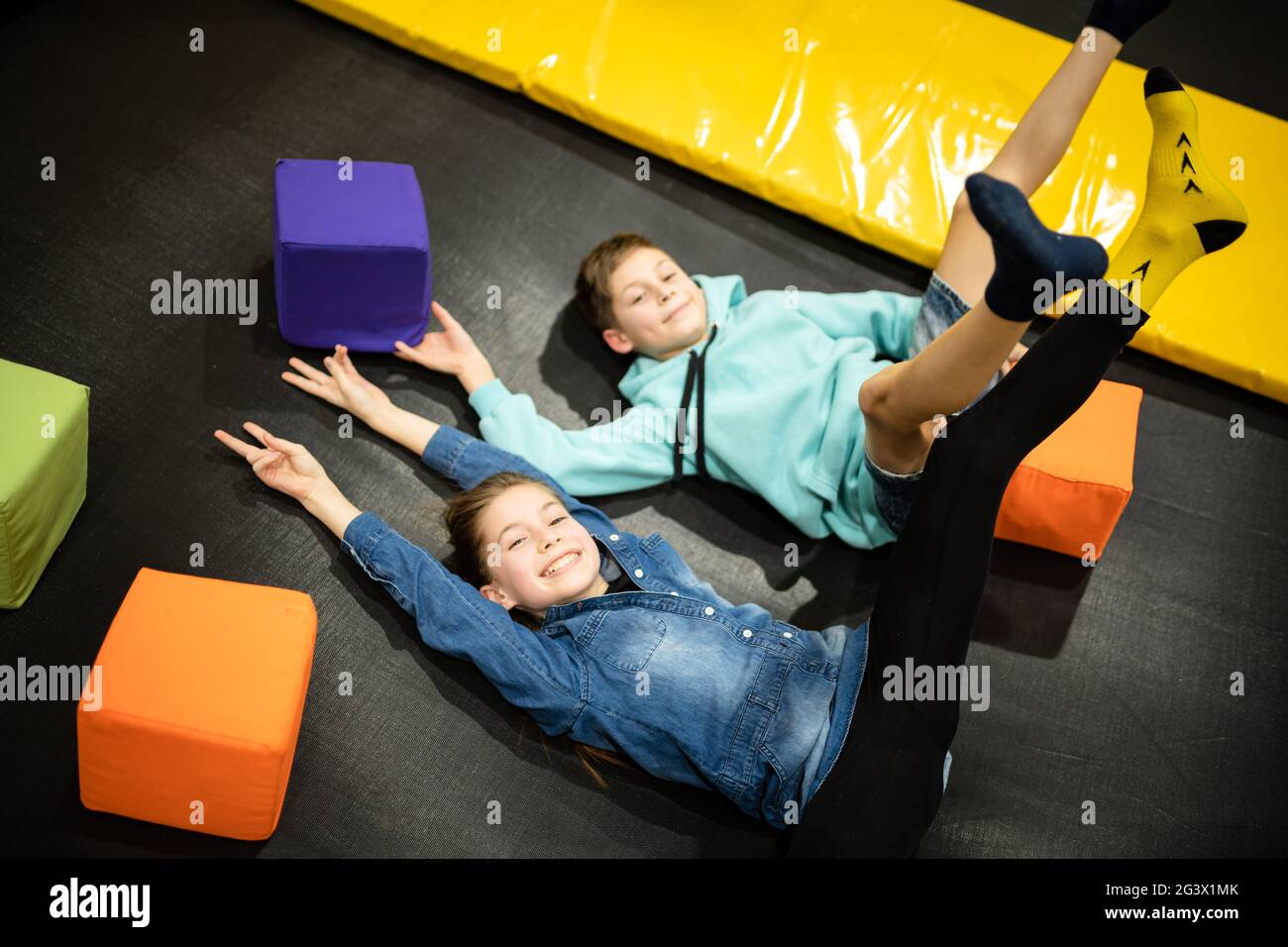 Happy smiling 11 years old kids jumping on trampoline indoors in entertainment center. Active children leisure, jumping and play Stock Photo