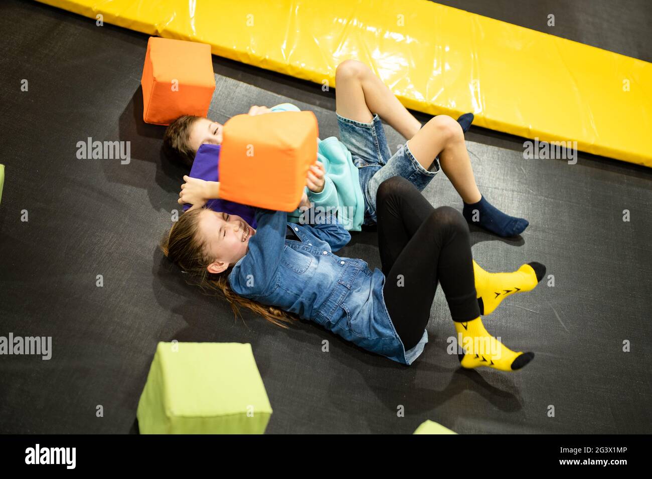 Cute twin brother and sister jumping and bouncing on indoor trampoline together when spending time in children play center. Spor Stock Photo