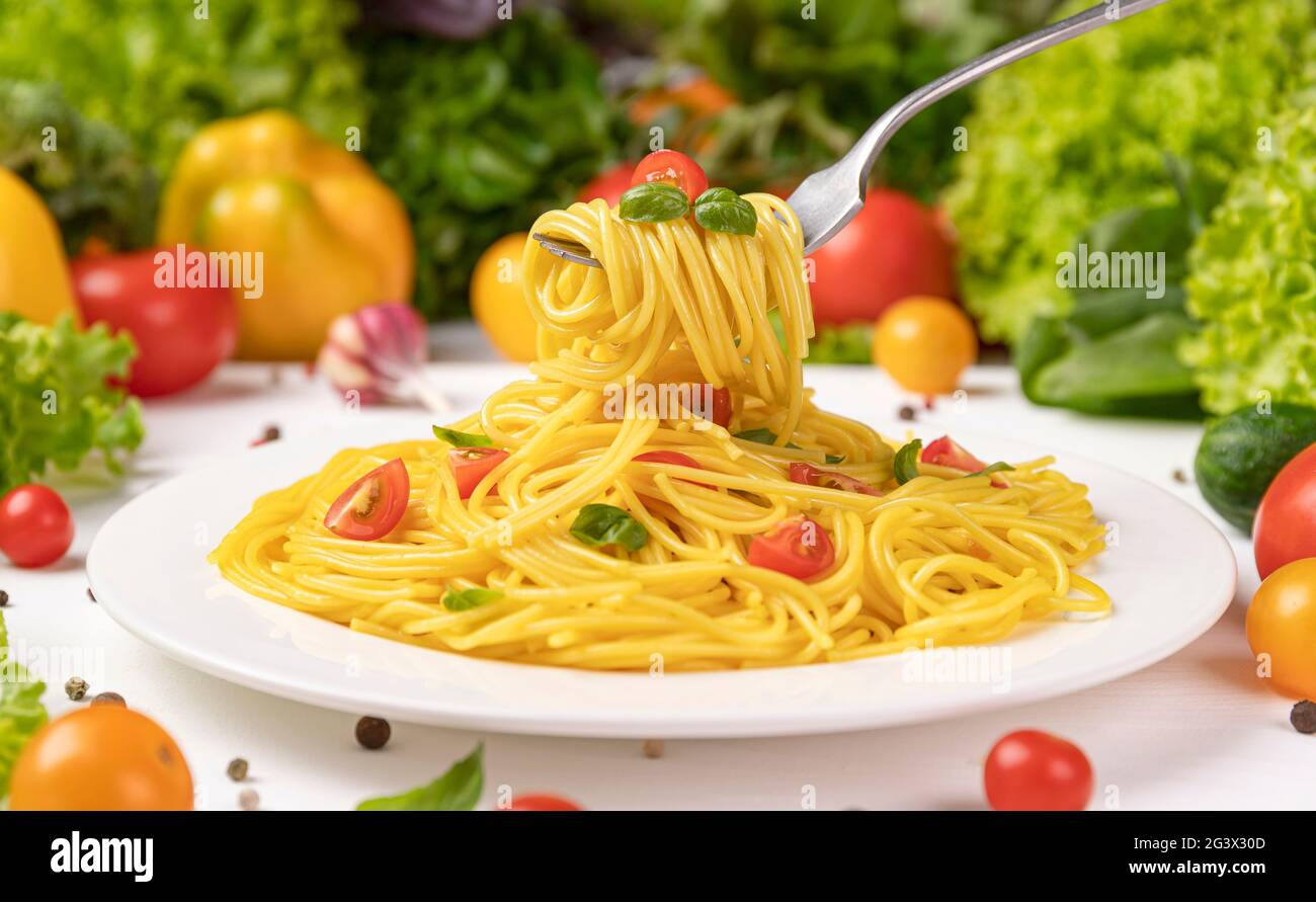 Italian pasta, spaghetti on fork with tomatoes and basil leaves Stock Photo